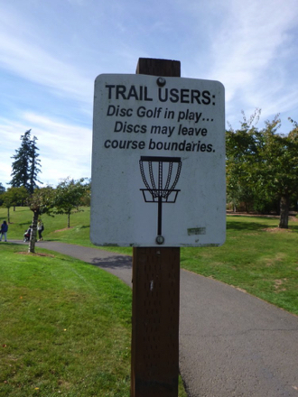 Disc golf sign along paved trail